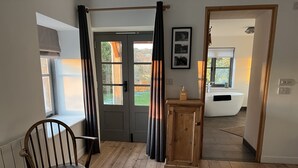 Un plancher en bois, une chaise, une porte, un meuble et une salle de bain avec une baignoire.