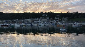 Un port de plaisance avec des bateaux amarrés, une eau calme et, en arrière-plan, des bâtiments et des arbres.
