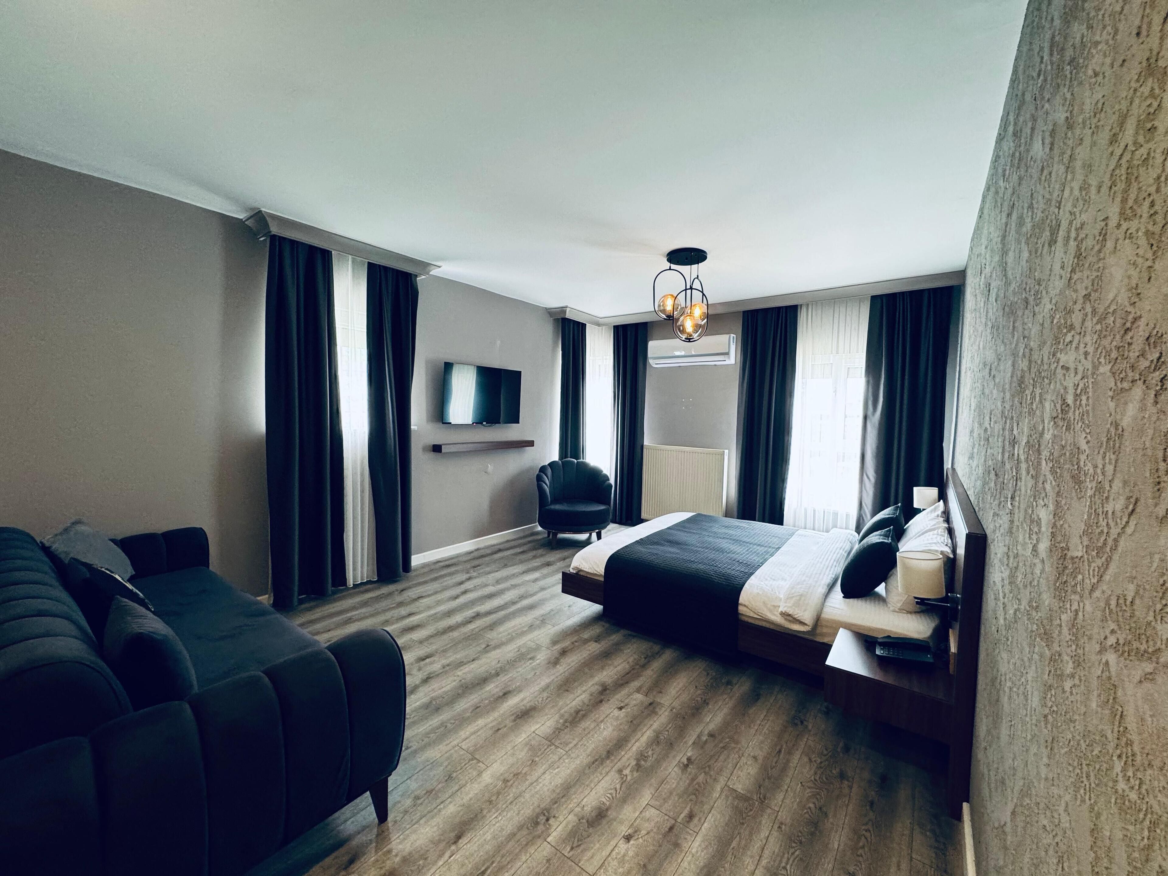 Una habitación de hotel moderna con una cama grande, un sofá, un televisor y una lámpara de techo.