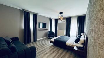 Una habitación de hotel moderna con una cama grande, un sofá, un televisor y una lámpara de techo.