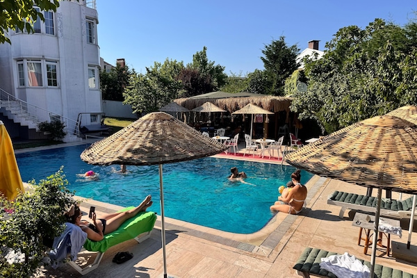 Una piscina al aire libre, sombrillas, sillones reclinables de piscina