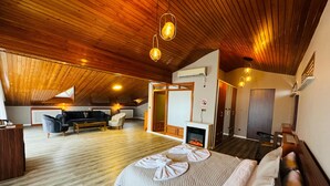 Um quarto espaçoso com uma cama grande, lareira, sofá e mesa de jantar.