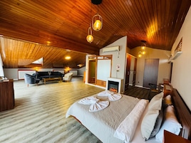 Una habitación amplia con una cama grande, chimenea, sofá y una mesa de comedor.