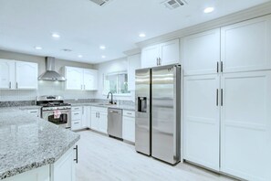 A modern kitchen with white cabinetry, stainless steel appliances, and a granite countertop. - Luxury home with Pool and gym and RV parking (Las Vegas)