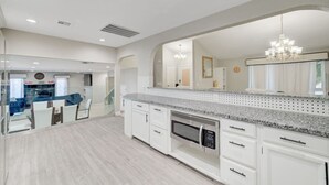 Een moderne keuken met witte kasten, granieten aanrechtbladen en een inbouwmagnetron.
