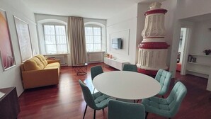 Una sala moderna con un sofá amarillo, una mesa redonda con seis sillas y un pilar decorativo.