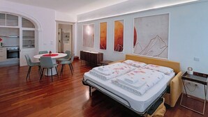 Un dormitorio moderno con cama, escritorio y área de comedor.