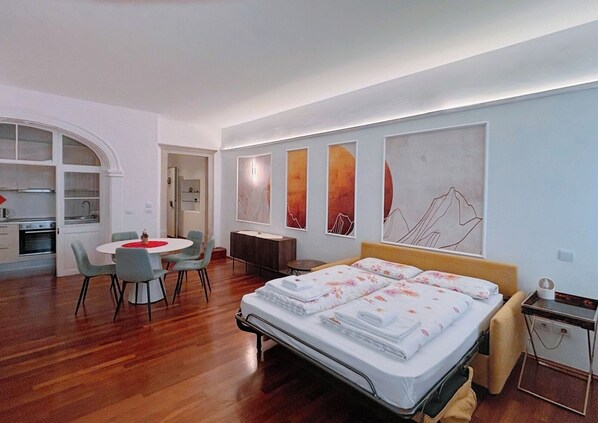 A modern bedroom with a bed, a desk, and a dining area.