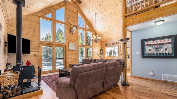 A spacious living room with a large brown sofa, a fireplace, and a wooden ceiling.