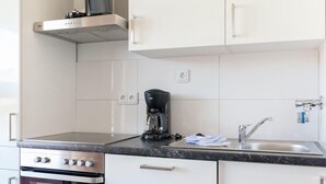 A modern kitchen with white cabinets, a built-in oven, a coffee maker, and a sink. - App. "syltliebe", Wohnung 6, 1 Etage (Sylt)