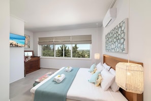 Quarto com uma cama grande, vista para árvores pela janela, cômoda de madeira e ar-condicionado fixado na parede.