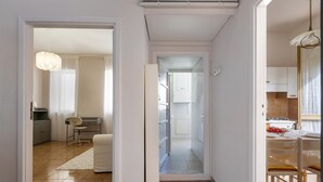 A modern kitchen with white cabinets, a dining area with a table and chairs, and a hallway leading to another room.