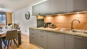 A modern kitchen with grey cabinets, a stainless steel sink, and a wooden countertop.