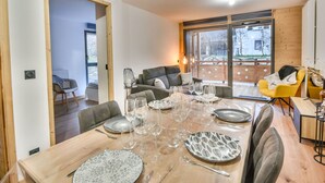 A dining area with a wooden table set for four, surrounded by modern furniture.