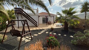 A patio area with a swing set, a covered seating area, and a pool.