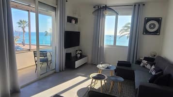 Un soggiorno moderno con balcone, TV e divano.