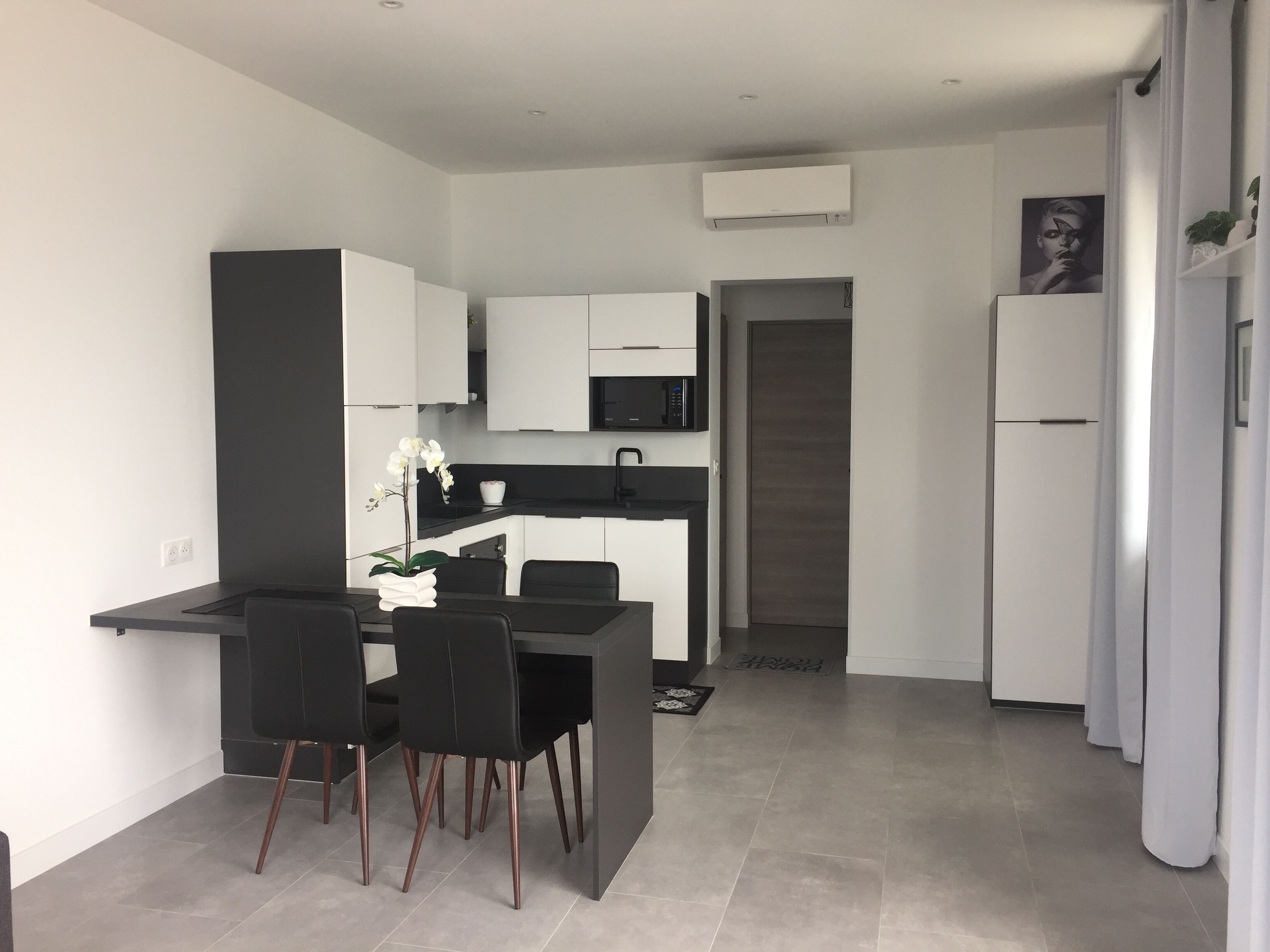 Una cucina moderna con mobili bianchi, un piano di lavoro nero e un'area pranzo con sedie nere.