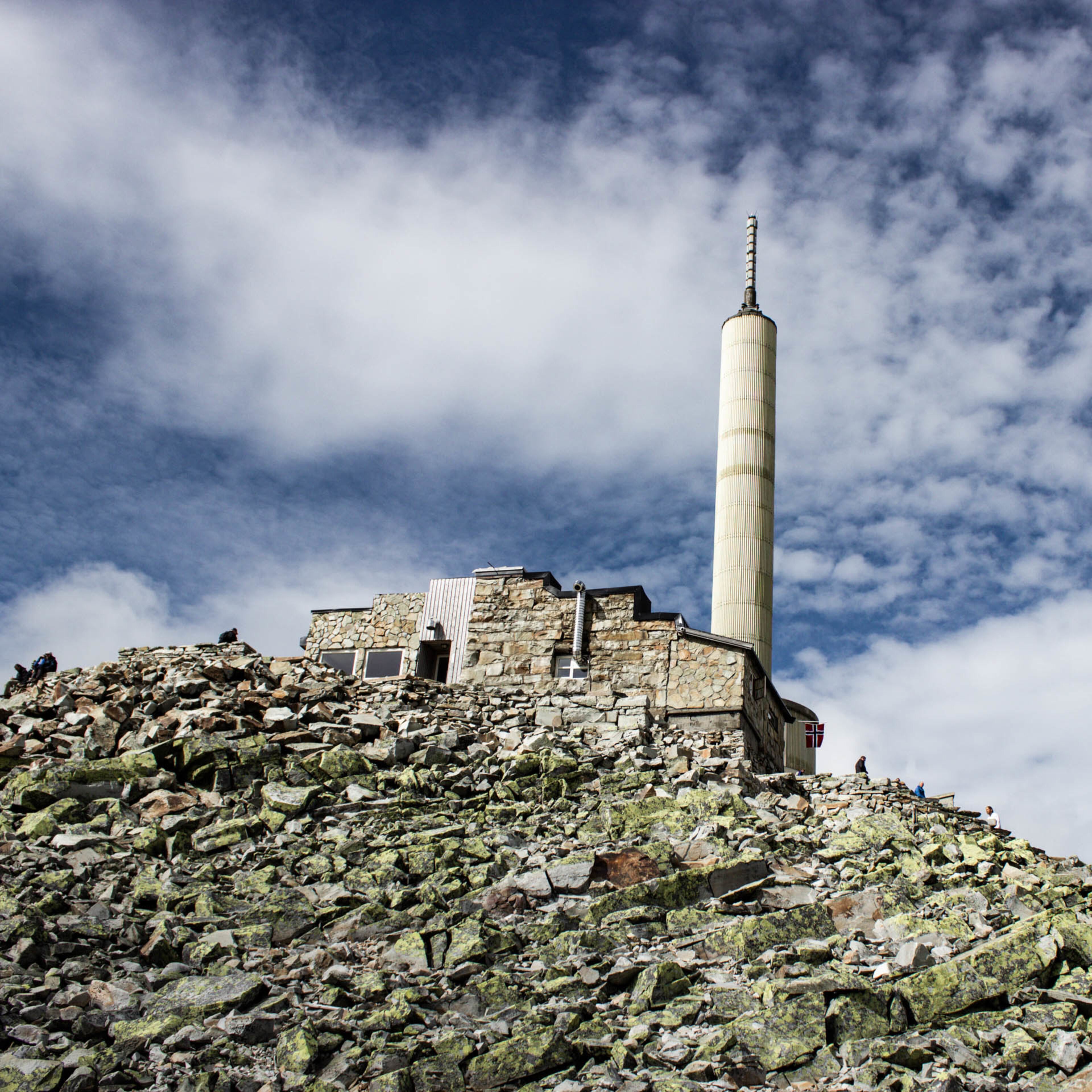 Un edificio de piedra con una torre alta y cilíndrica sobre una colina rocosa.