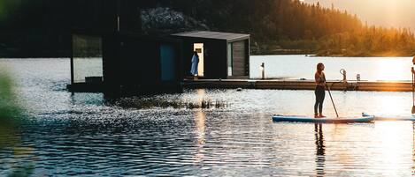 Un lago tranquilo con un muelle de madera y una cabaña pequeña.