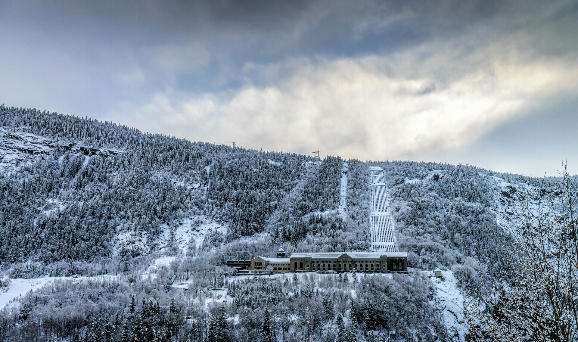 A snow-covered mountain with a building at the base.