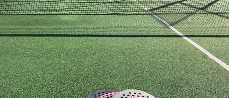 Una cancha de tenis con una red, una raqueta y una pelota en el suelo.