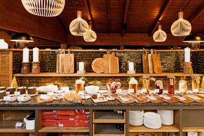 Un buffet de petit-déjeuner proposant une variété d’aliments et d’ustensiles, des planches à découper en bois et des ustensiles suspendus.