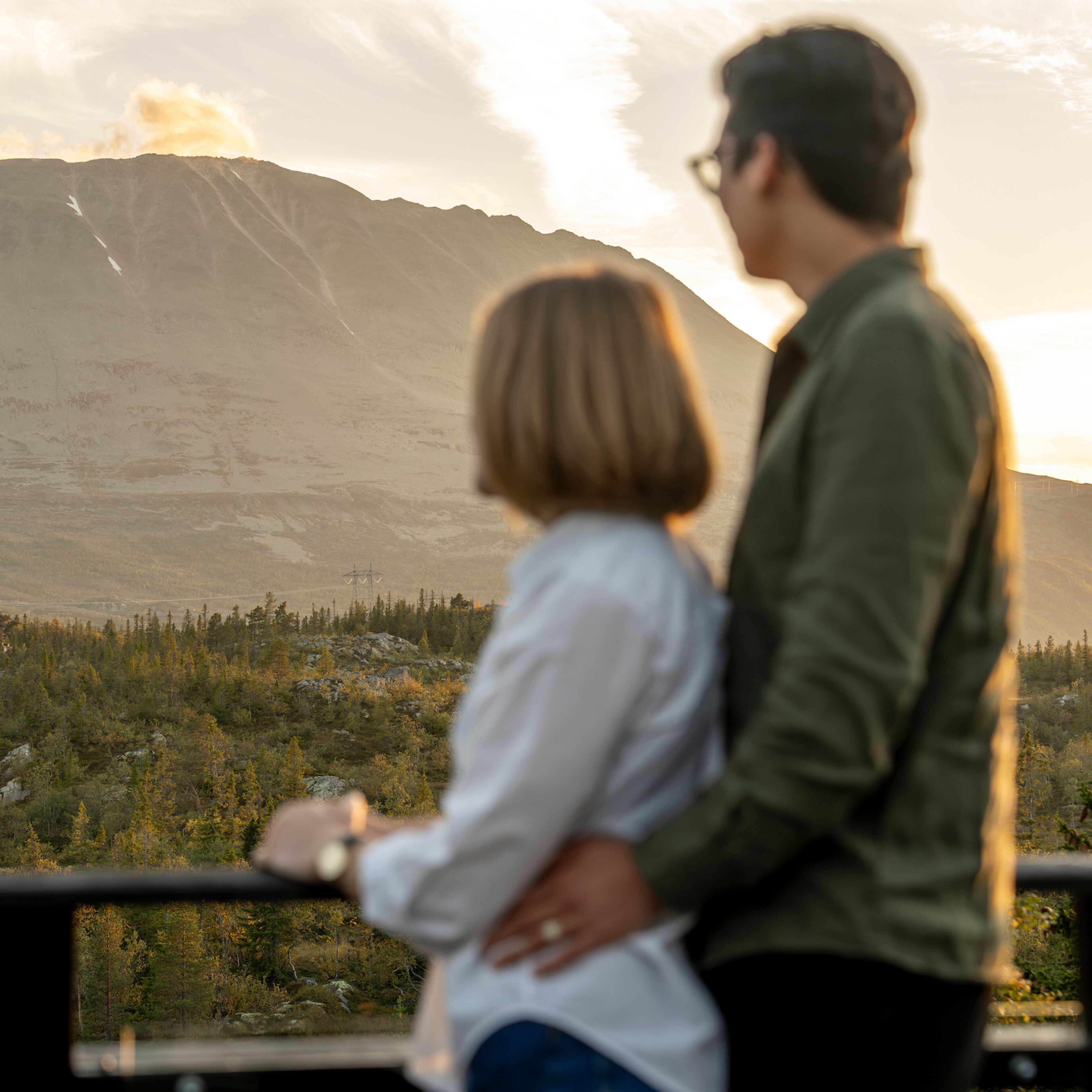 Un couple s’embrasse, avec un paysage montagneux en arrière-plan.