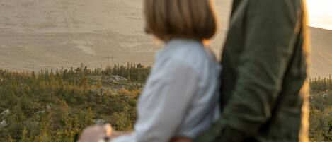 Un couple s’embrasse, avec un paysage montagneux en arrière-plan.