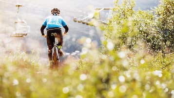 A mountain biker on a trail with a cable car in the background.