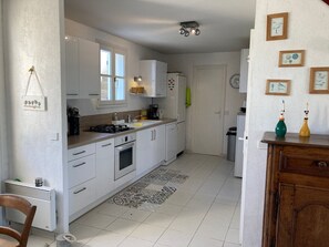 Une cuisine de taille réduite avec des meubles blancs, une cuisinière à gaz et une machine à café.