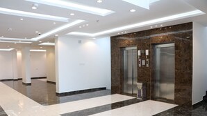 A modern hotel lobby with a marble floor, two elevators, and recessed ceiling lighting. - Qimam Park Hotel 3 Abha (Abha)