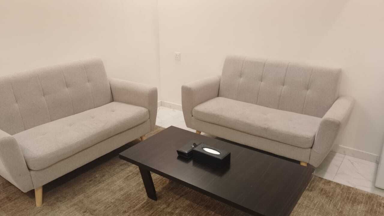 A living room with two beige sofas and a dark wooden coffee table.