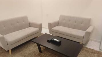 A living room with two beige sofas and a dark wooden coffee table.