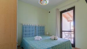 Ein Schlafzimmer mit einem Bett, einem Nachttisch, einem Fenster und Blick ins Freie.