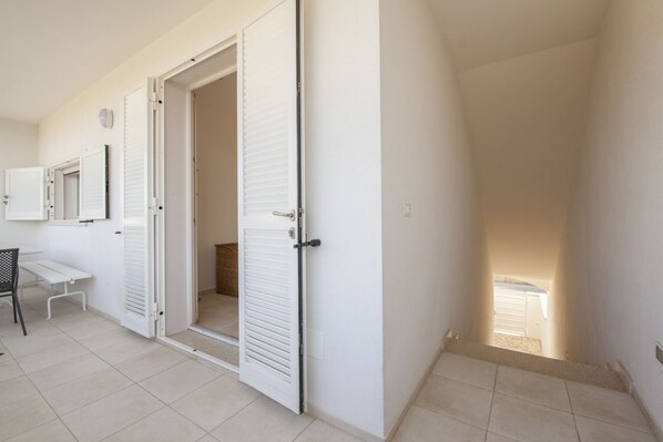 A hallway with a white door, a small table, and a chair.