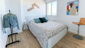 A bedroom with a bed, a chair, a desk, and a clothing rack. - Apartment by the sea with exceptional views (Soorts-Hossegor)