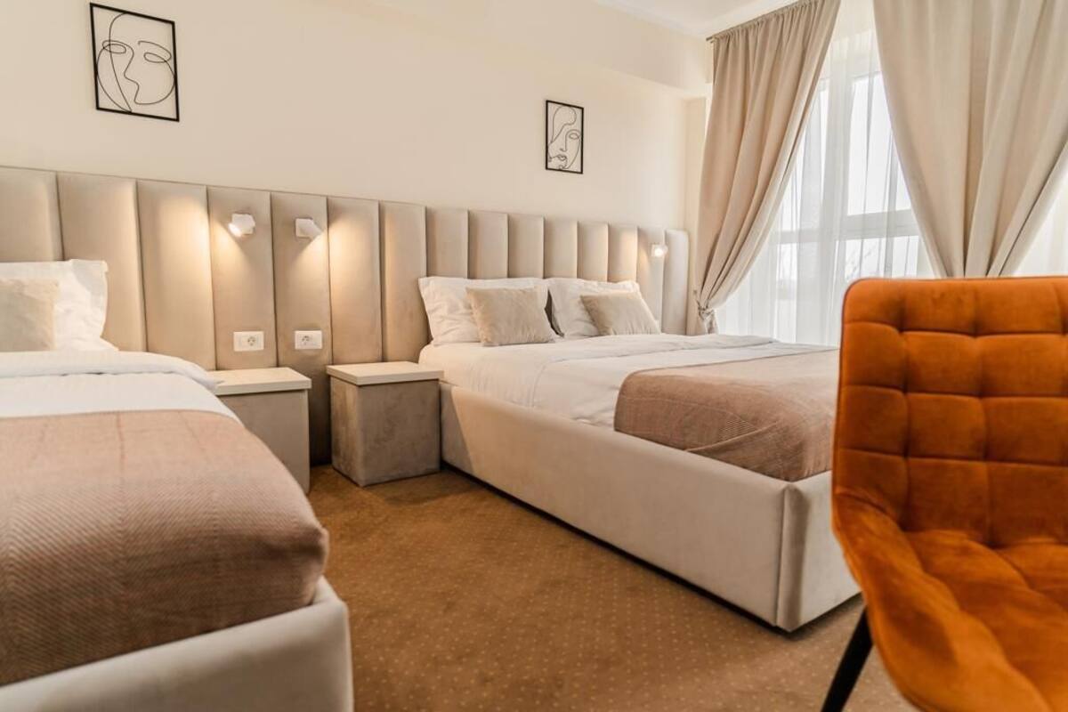 Une chambre d’hôtel avec deux lits, une table de chevet, une chaise et des œuvres d’art accrochées aux murs.