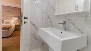 A modern bathroom with a white sink, marble walls, and a visible shower area. - PENSIUNEA ELISEI (Timisoara)