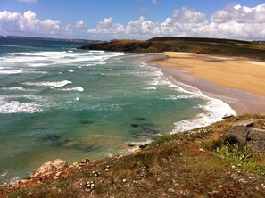 A coastal landscape with a sandy beach and rocky cliffs.