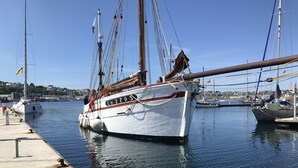 A white yacht docked at a marina with a clear sky.