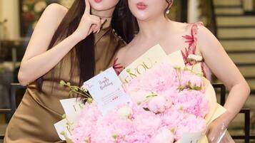 Dos personas sosteniendo un ramo de flores rosas y una tarjeta con el mensaje 'Happy Birthday'.