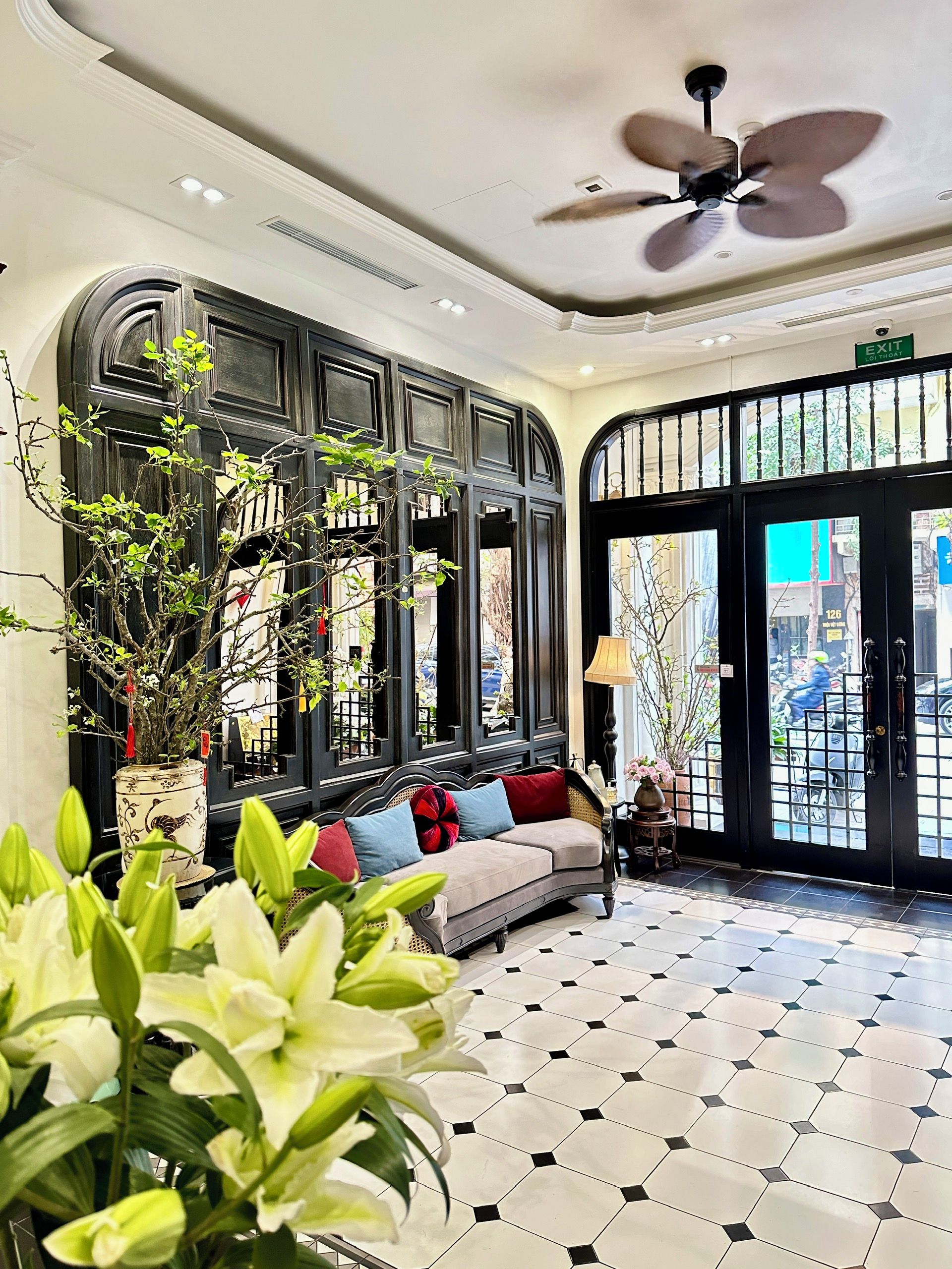 A lobby with a sofa, a ceiling fan, a potted plant, and a tiled floor.