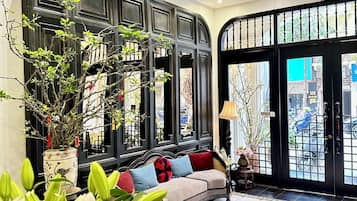 A lobby with a sofa, a ceiling fan, a potted plant, and a tiled floor.