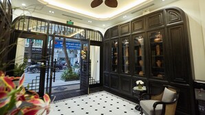 A hotel lobby with a black and white tiled floor, a ceiling fan, and a reception desk with a chair. - Camellia Residence Hanoi (Hanoi)