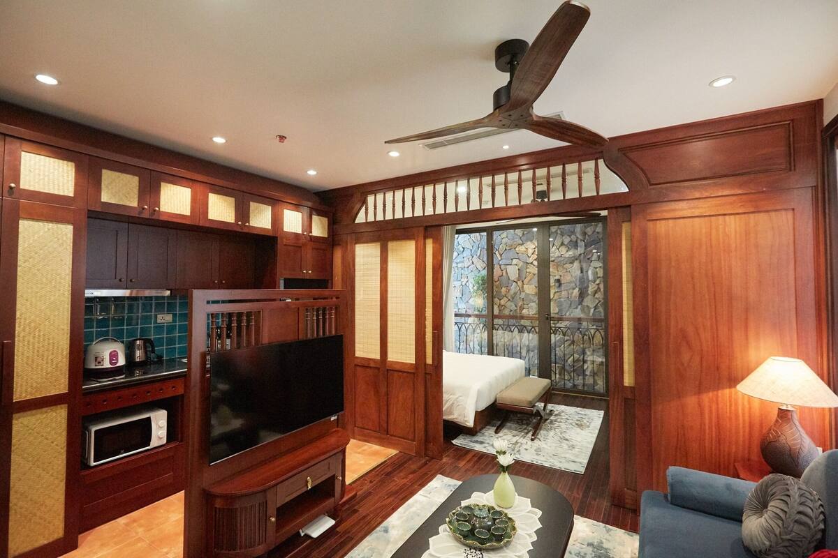 A traditional wooden interior with a television, wooden cabinets, a dining table, and a sofa.