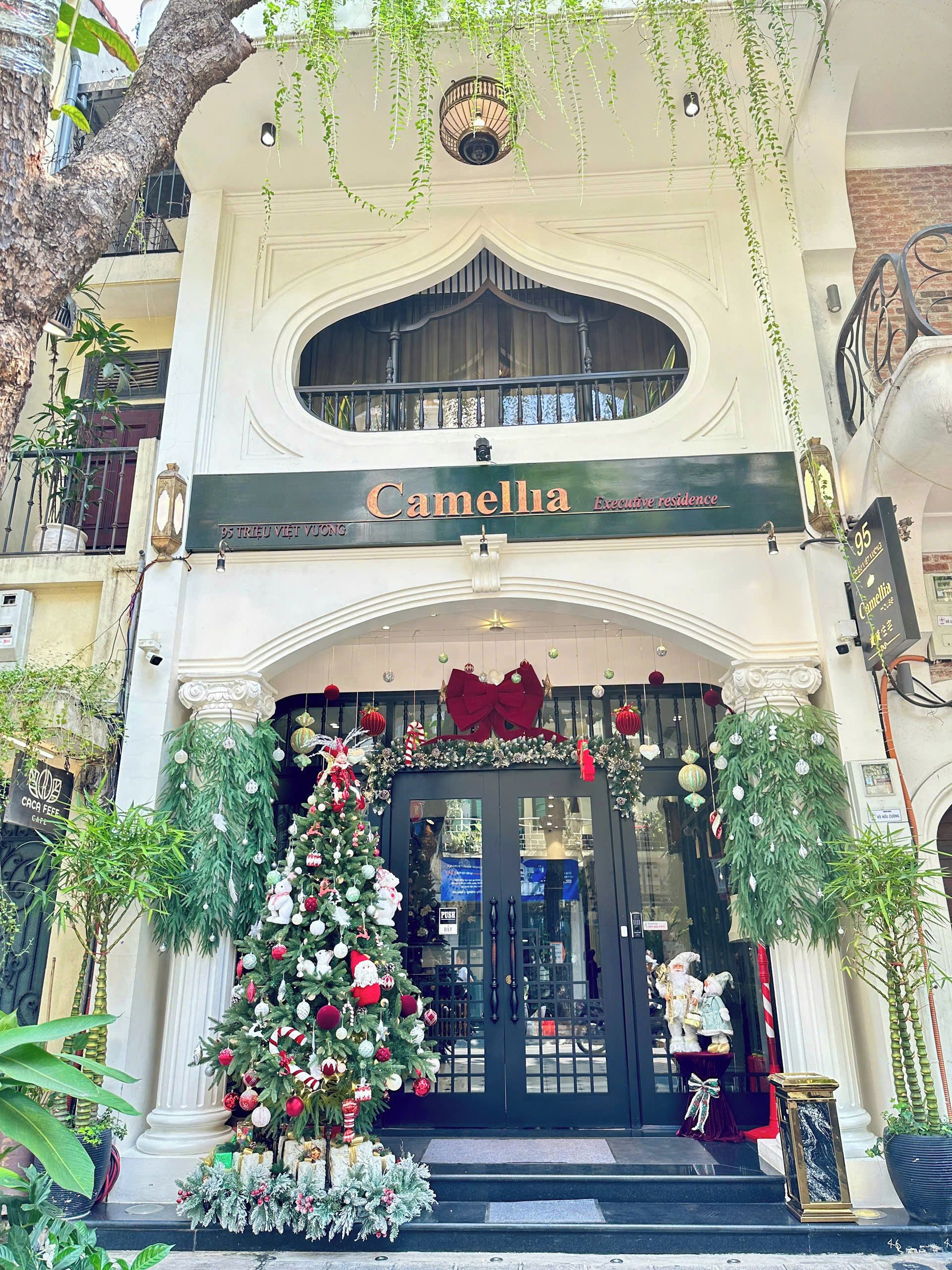 A building facade with a sign reading 'Camellia Executive Residence' and a Christmas tree decorated with ornaments.