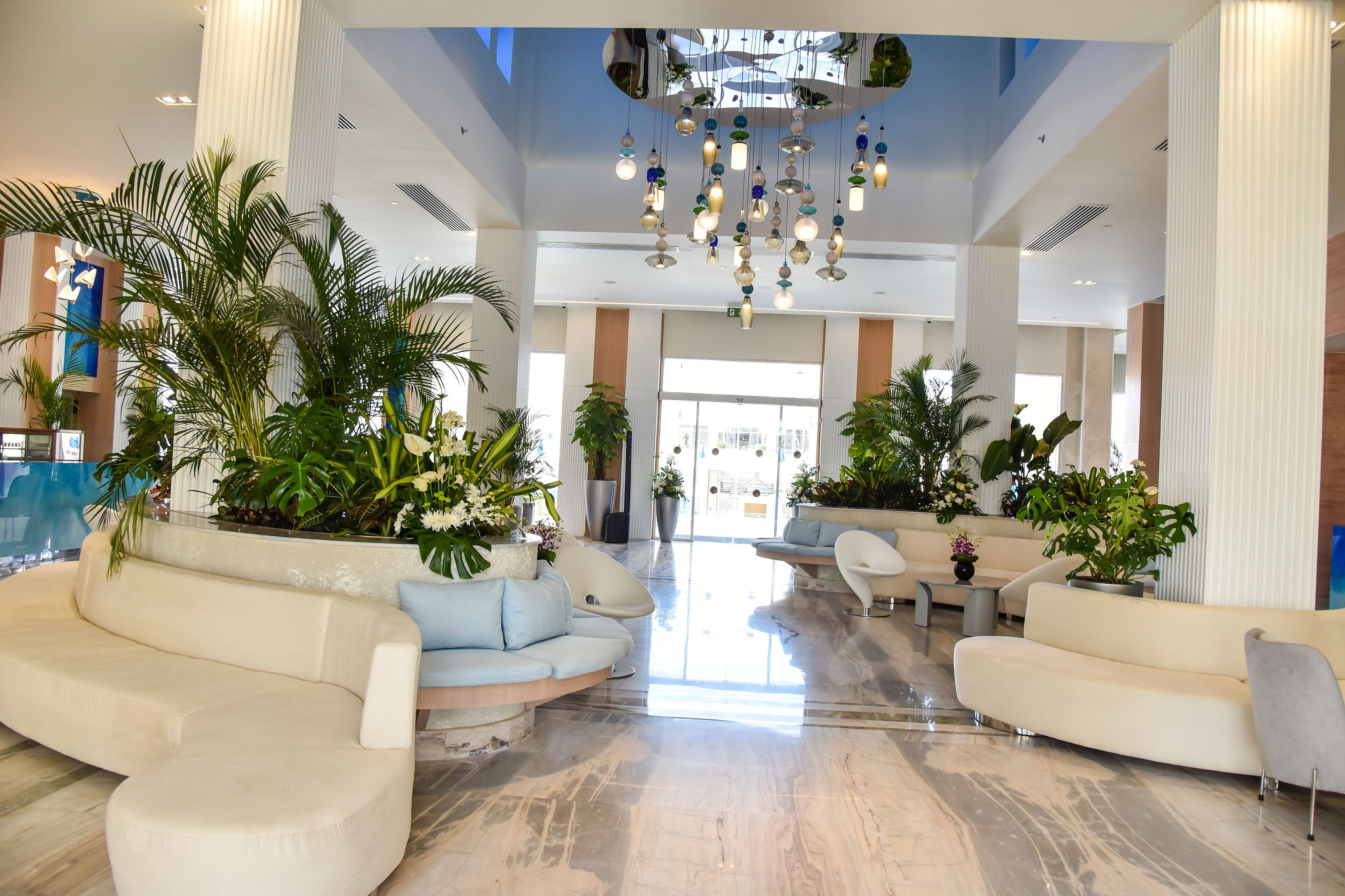 Eine geräumige Lobby mit hoher Decke, modernen Kronleuchtern und mehreren Sitzbereichen.