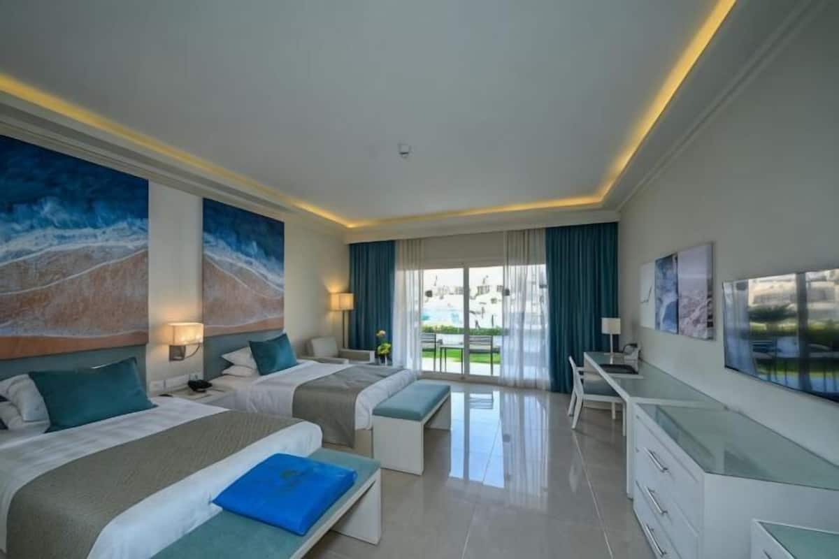 Une chambre d’hôtel avec deux lits, un bureau et une vue sur l’extérieur.