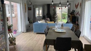 Un comedor con una mesa dispuesta para dos personas, un sofá azul y un árbol de Navidad al fondo.