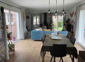 Uma área de refeições com uma mesa posta para dois, um sofá azul e uma árvore de Natal ao fundo.